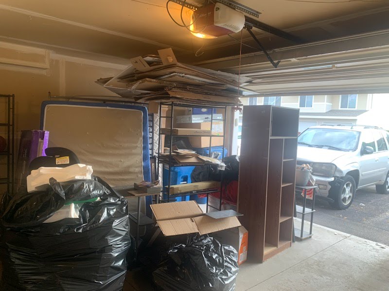 Flattened cardboard, shelving and household items in an open garage