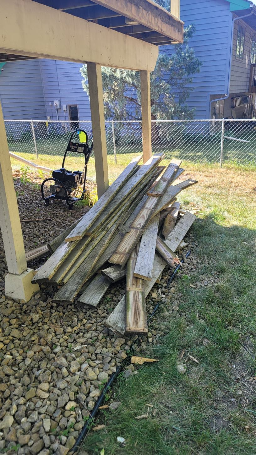 Detached weathered boards gathered outside beneath a deck